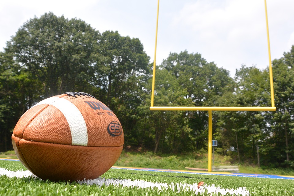 Football on the ground with yellow field goal post in background